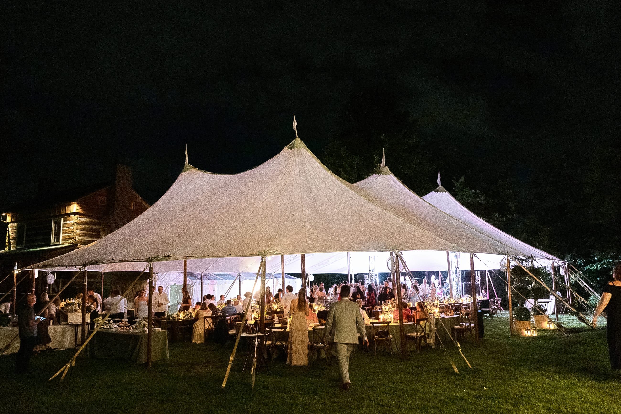The sailcloth tent glowing on the lawn after dark